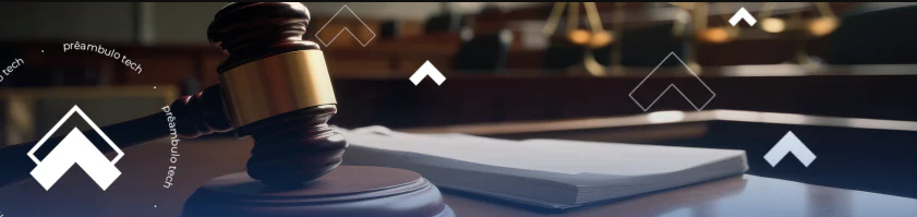 Martelo do juiz sobre mesa com livro aberto ao fundo, representando ambiente de tribunal