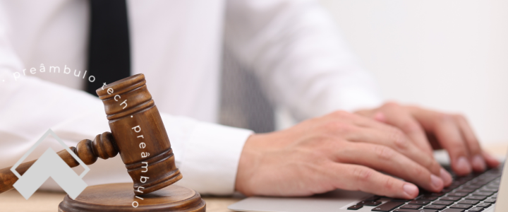 Advogado utilizando computador com martelo do juiz ao lado representando o uso de tecnologia e software jurídico na advocacia